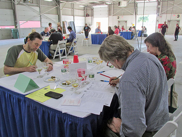 Men and woman at a table writing on judge sheet at wine contest