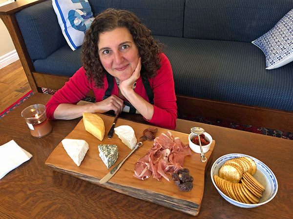 A woman smiling with a cheese charcuterie board