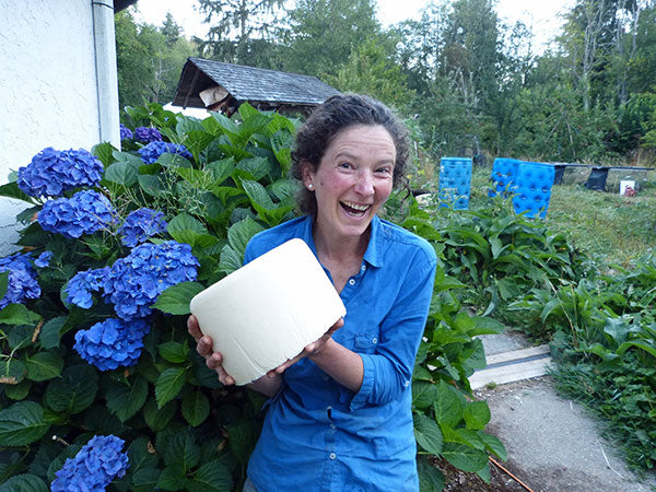 Lady smiling while holding block of cheese in backayard