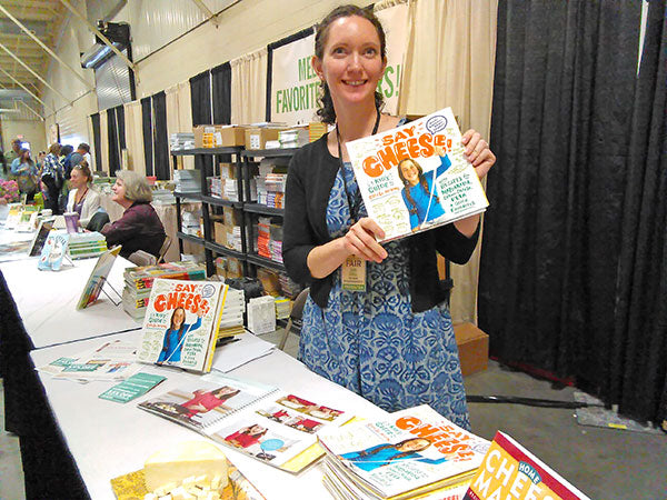 Woman holding up "Say Cheese" at a book signing