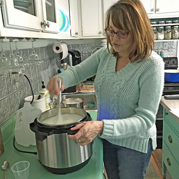 person making homemade mozzarella in instant pot in kitchen at home