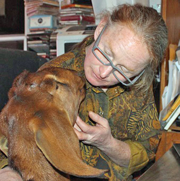 Man kissing head of goat in his house