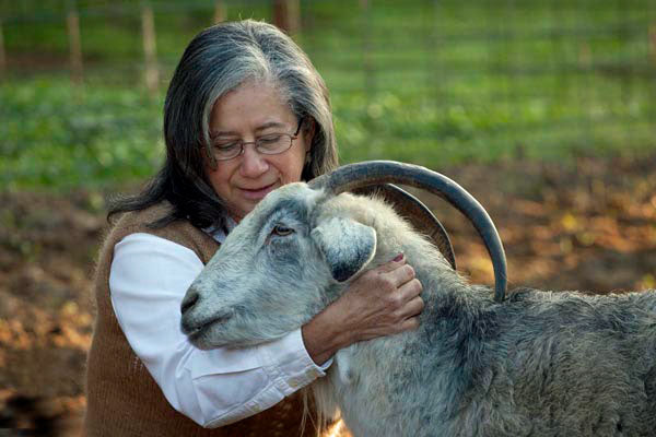 a woman petting a goat