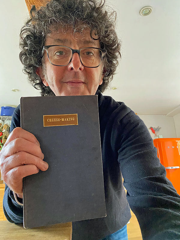 A woman holding a cheesemaking book