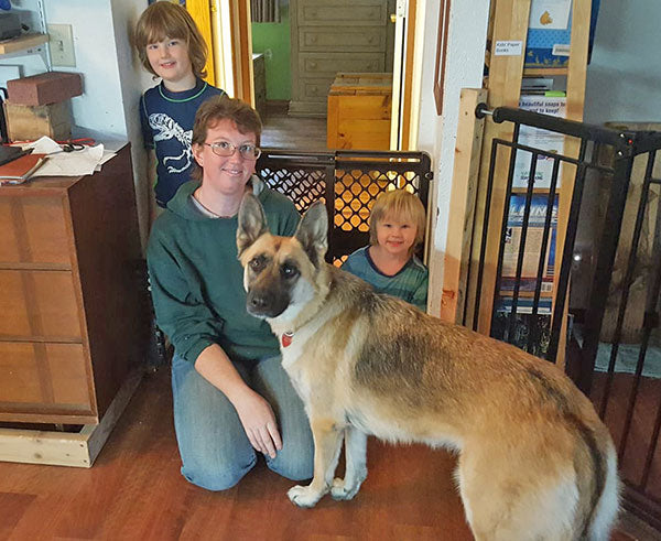 Three kids with their German Shepard in a house