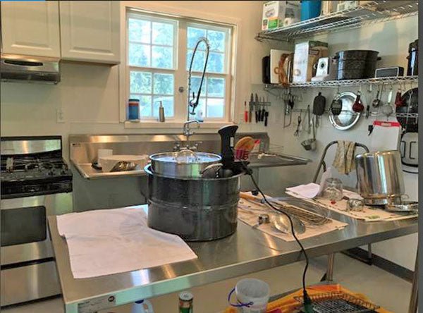 Cheese making room with sink, large table, and ladles