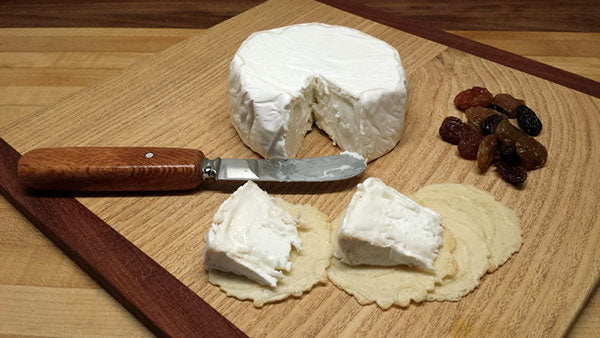 Block of cheese with knife and cut out pieces next to it