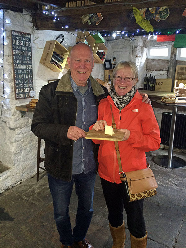 A man and woman smiling with a piece of cheese.